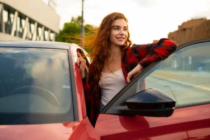 Joven en concesionario con su coche para jóvenes de ocasión