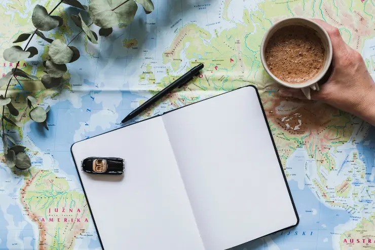 plano-coche-cafe Mesa con una libreta y cafe para planificar el viaje