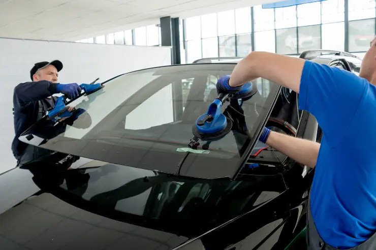 Mecánicos reparando la luna de un coche negro
